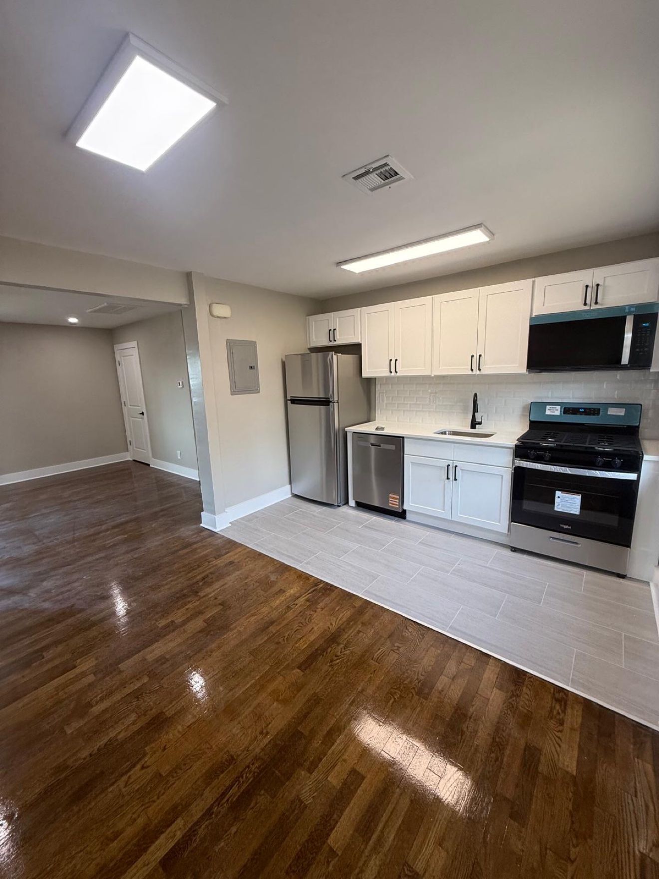 Cocina de apartamento con gabinetes blancos y manijas negras
