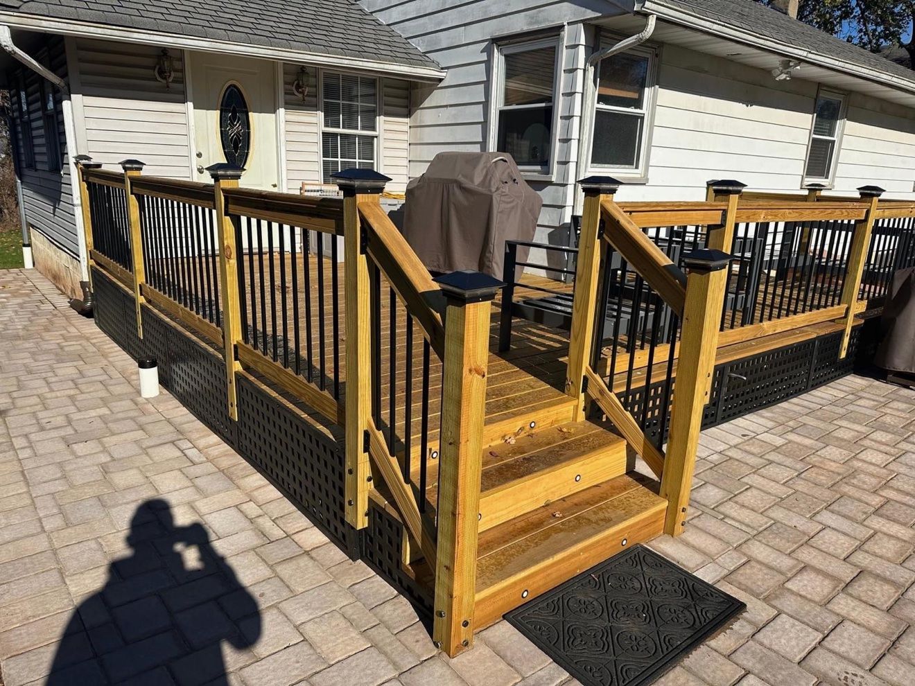 Deck nuevo en tono miel con balaustres negros y patio de adoquines