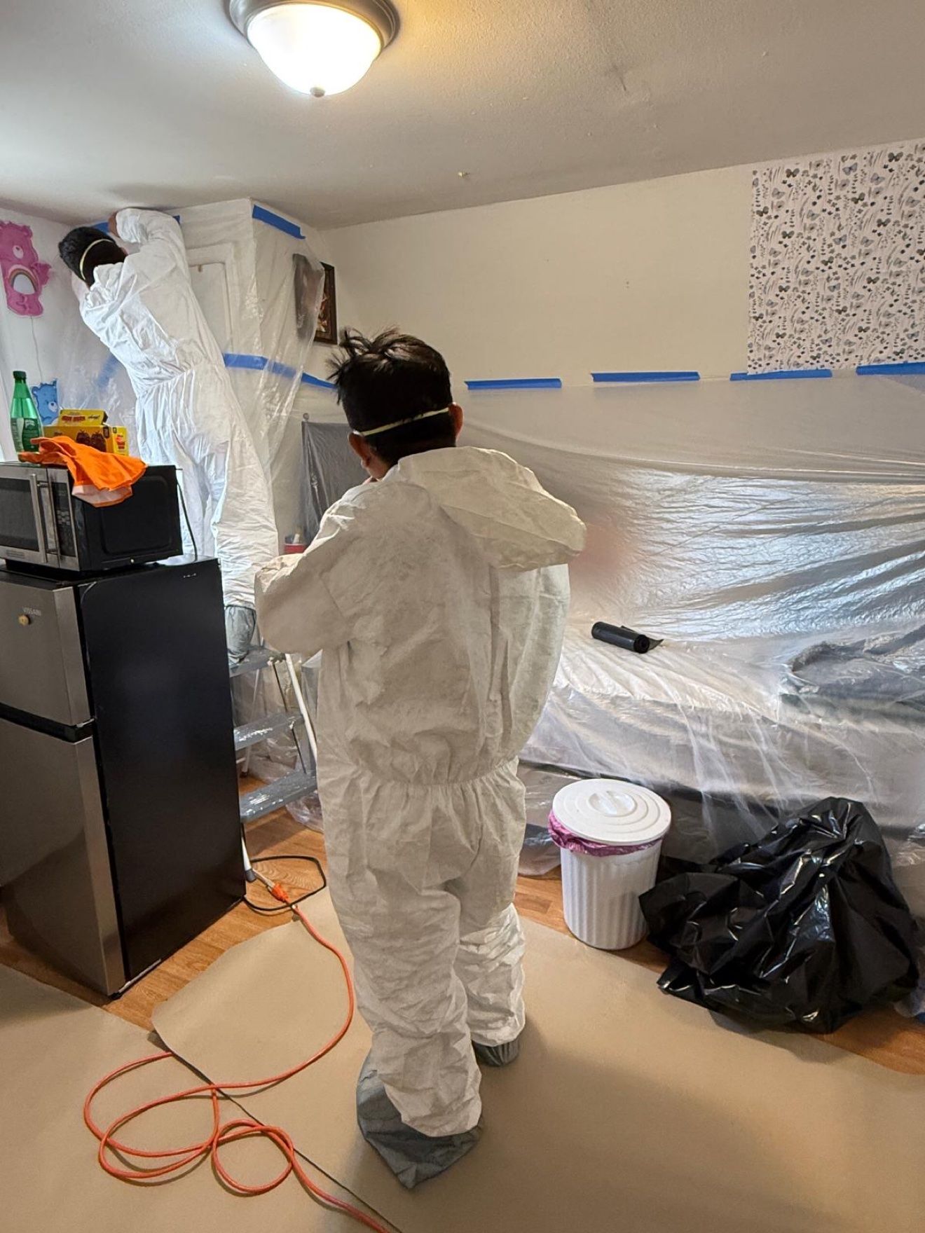 Equipo sellando la contención de plástico en un dormitorio