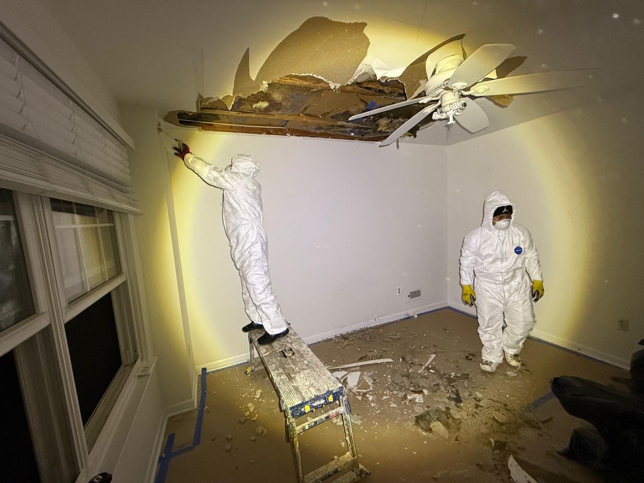 Técnico en una plataforma retirando el drywall dañado del techo