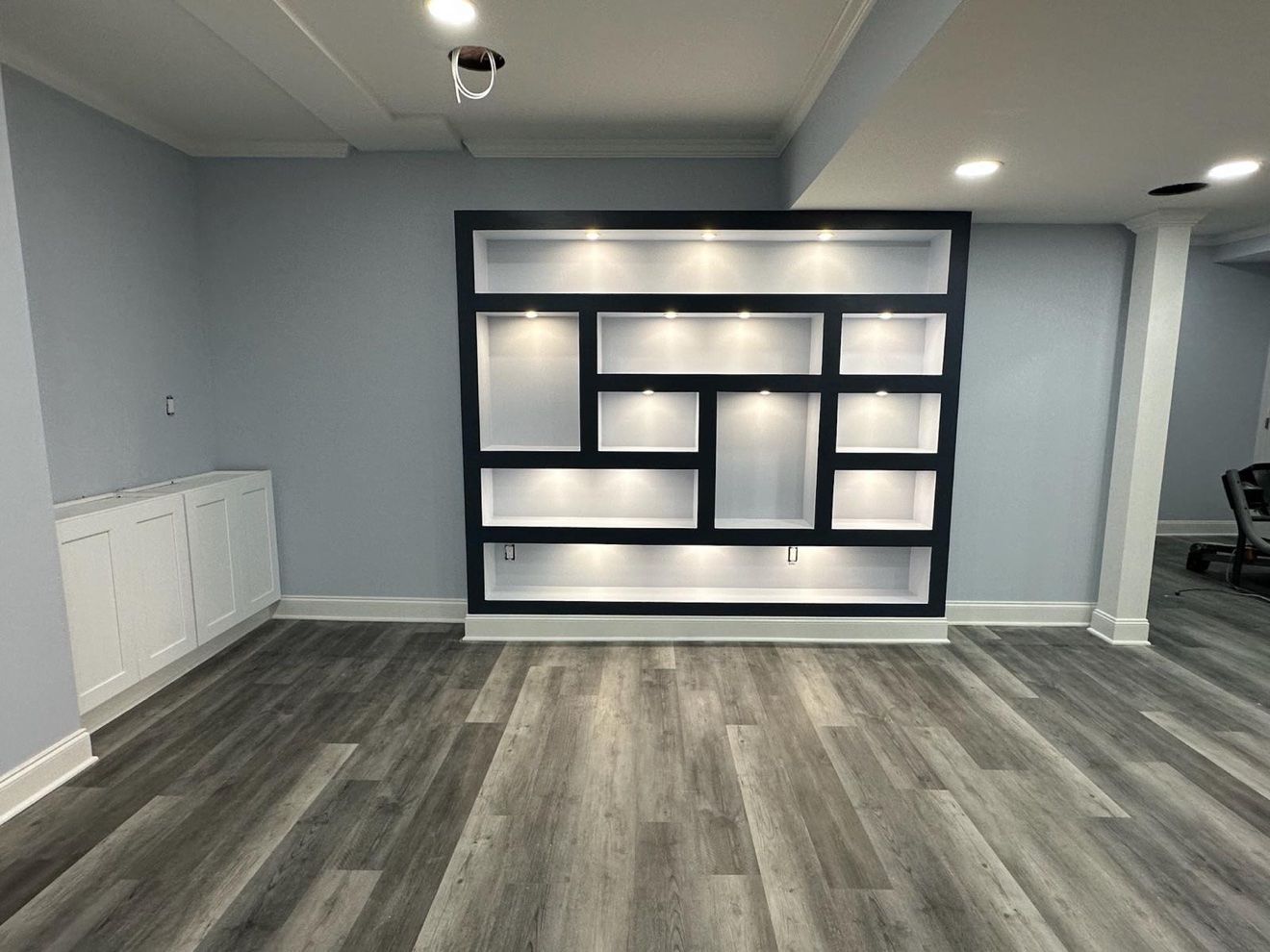 Sótano terminado con pared de estantería empotrada iluminada
