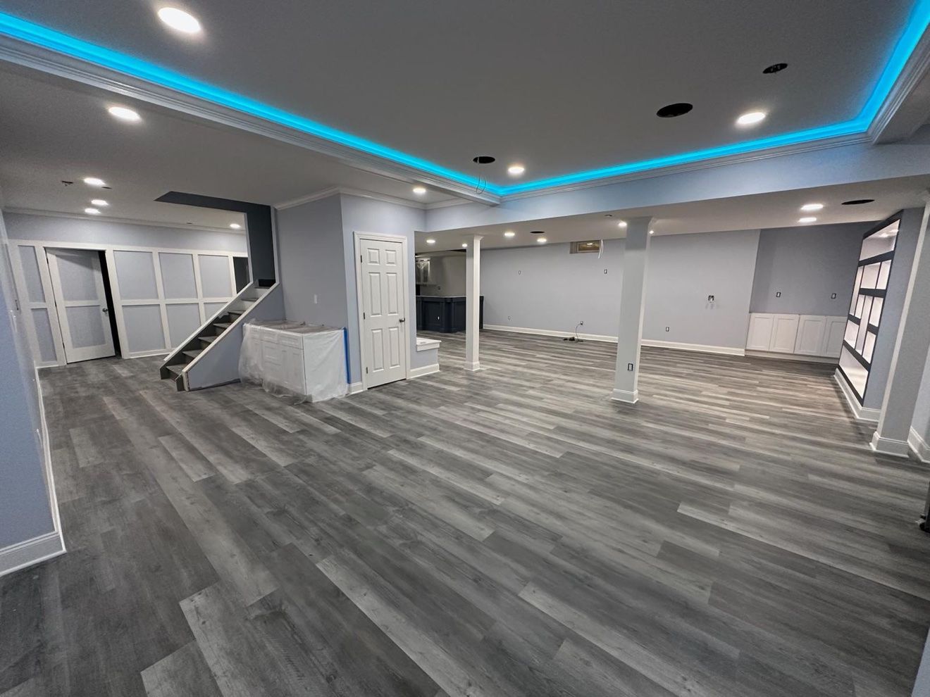 Sótano terminado con luz LED azul en el techo y escaleras